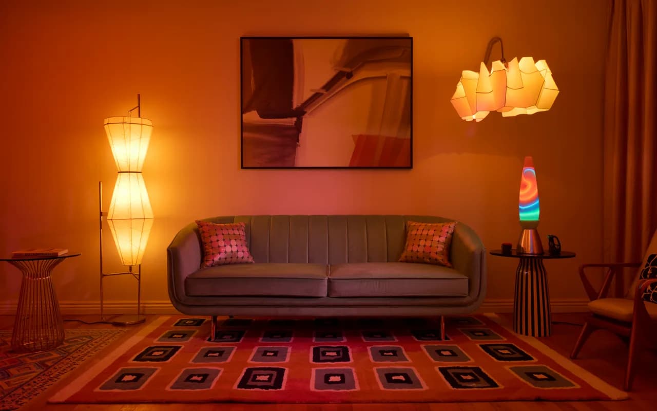 “Retro 80s living room with neon lights, lava lamp, geometric floor lamp, glowing ambient lighting, velvet sofa and bold rugs”