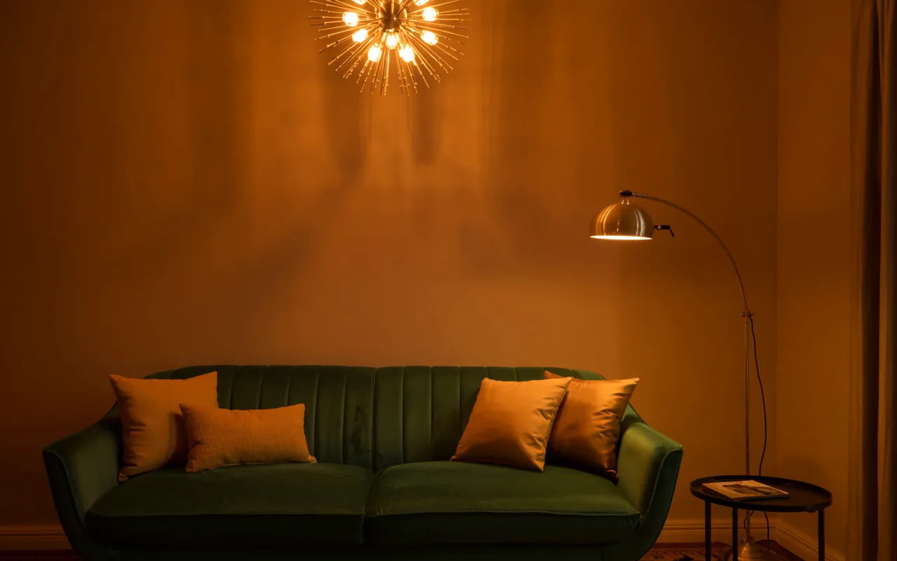 Retro living room with a sputnik chandelier, brass floor lamp, and warm ambient lighting highlighting a mid-century sofa.