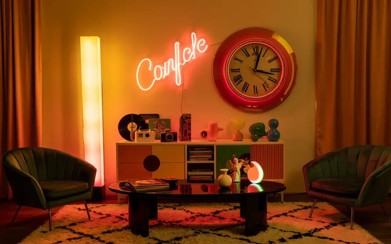 2000s living room with neon wall sign, oversized retro clock, glossy coffee table, layered retro decor, vibrant atmosphere”