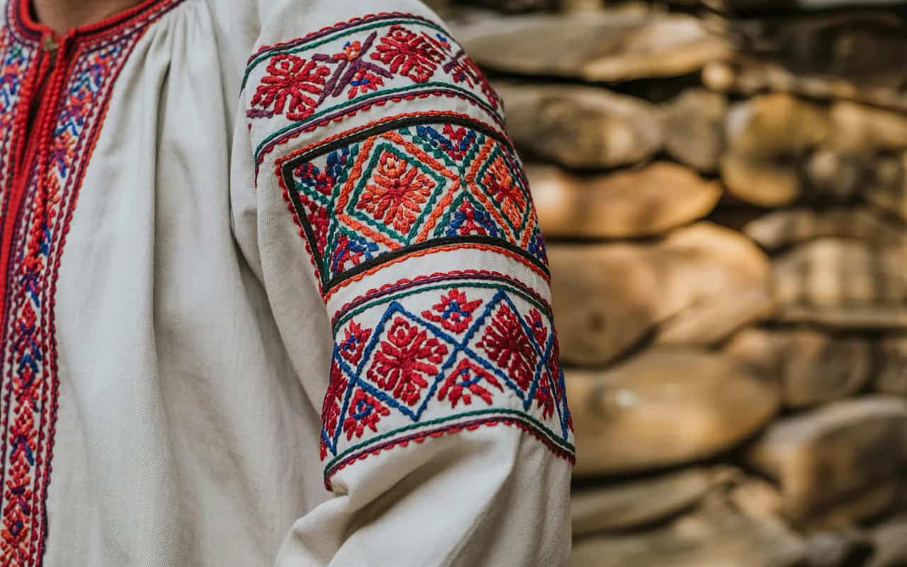 Close-up of traditional folklore fashion embroidery, showing intricate patterns and craftsmanship, warm natural lighting, authentic cultural background