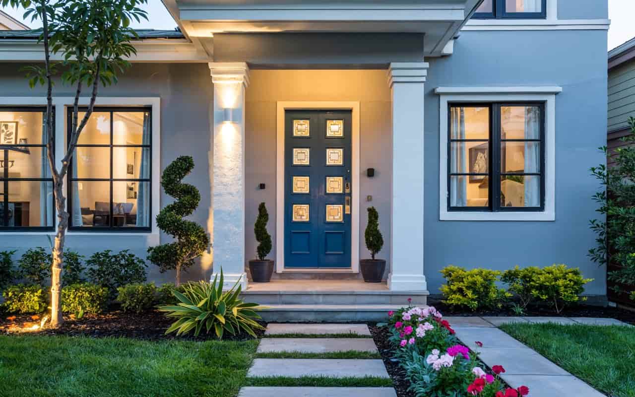 Beautiful home exterior with lush green lawn, colorful flower beds, trimmed shrubs, stone pathway, Pinterest-style garden, vertical 4K image