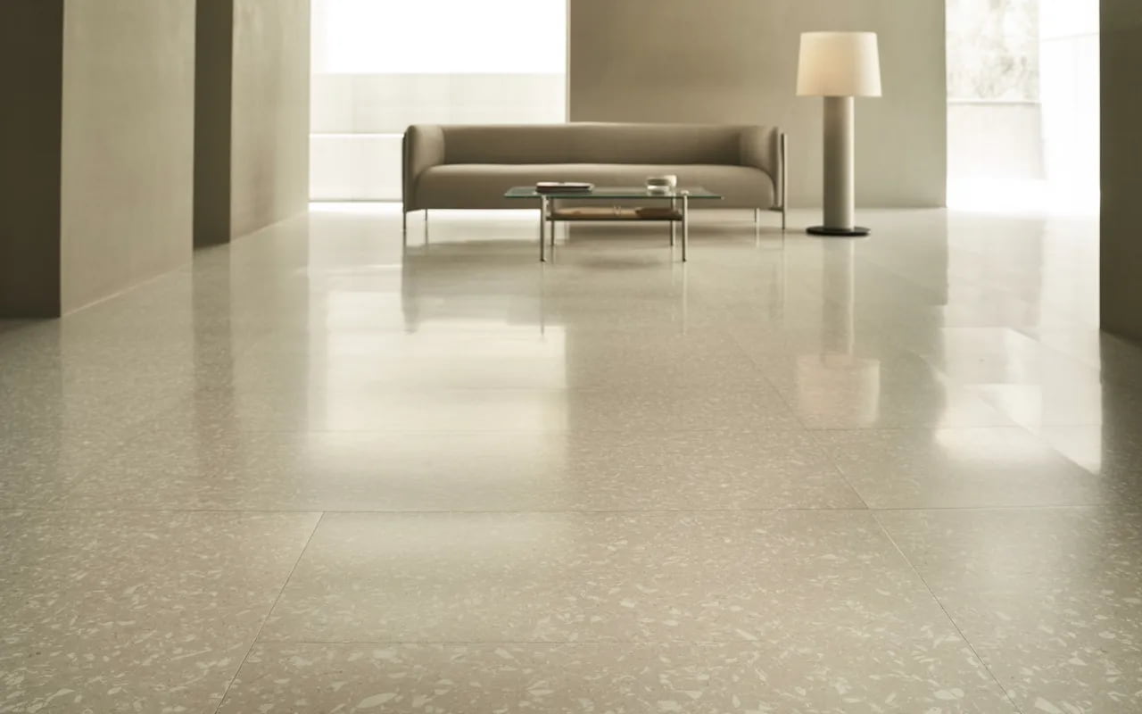 Small modern living room with light terrazzo flooring and minimal furniture.