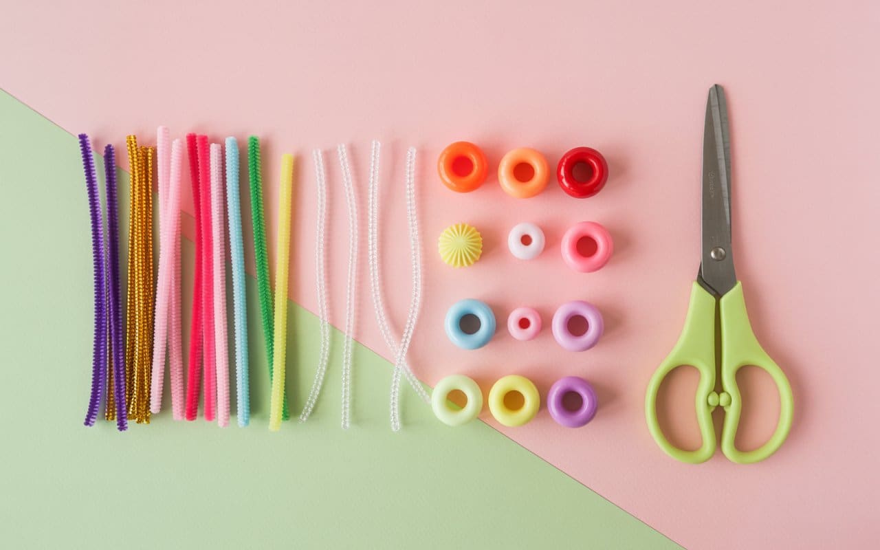 Minimalist photo of pipe cleaners, beads, and scissors arranged neatly on a craft table, pastel background, Pinterest DIY vibe
