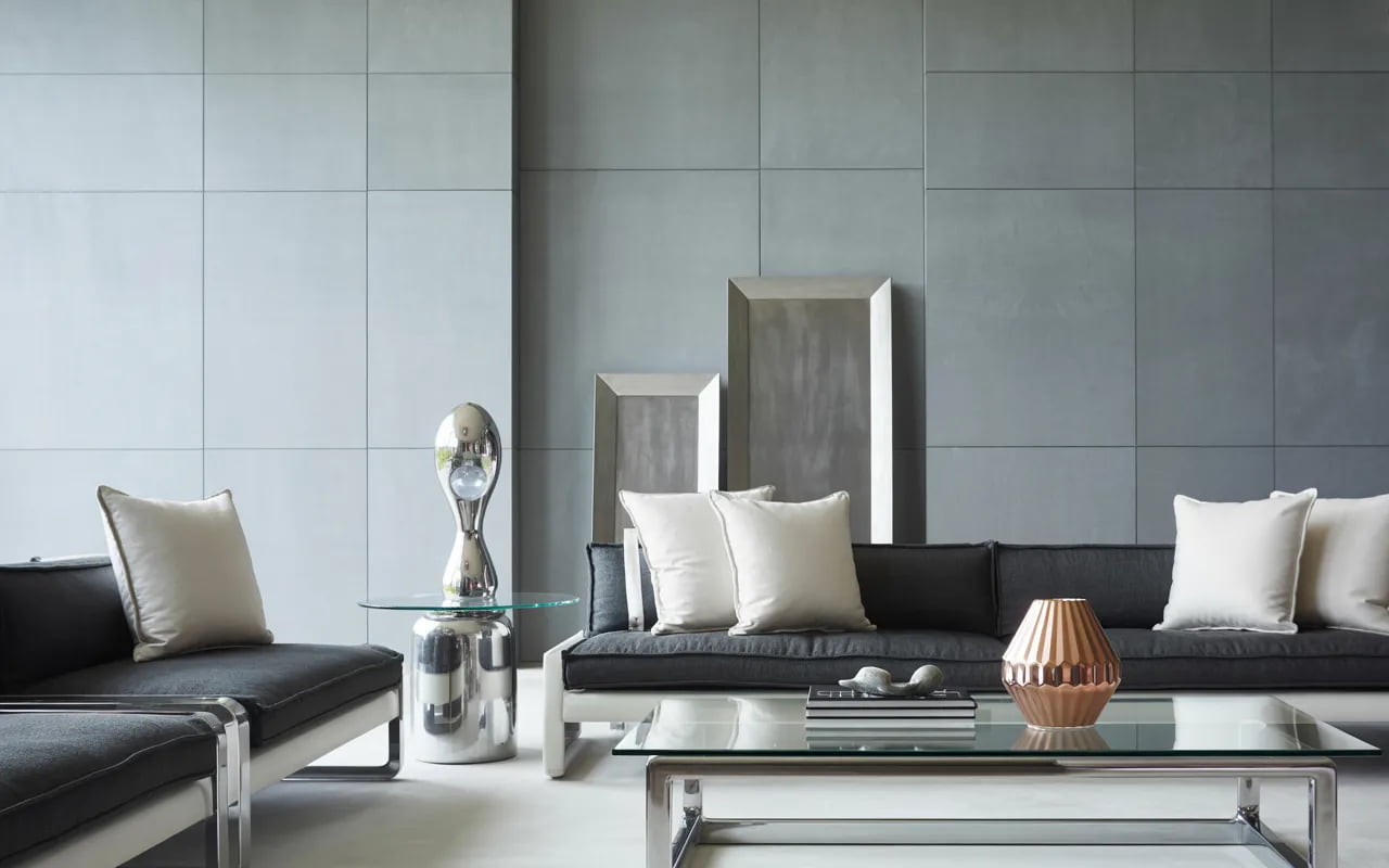 Modern living room with light grey walls, sleek furniture, and metallic decorative pieces