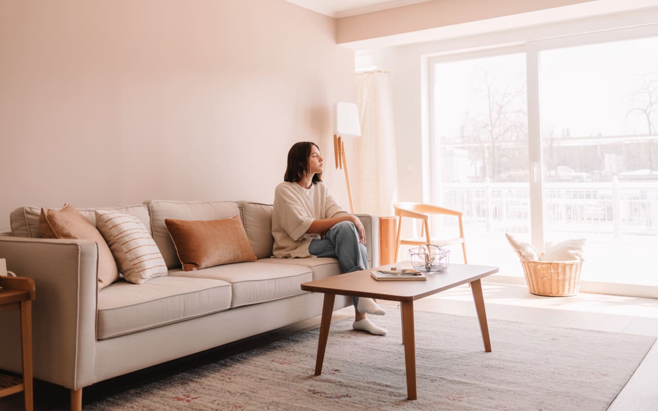 “Living room with neutral sofa centered on rug, facing large window, minimal décor, wooden coffee table, bright airy interior, Pinterest-style photo.”