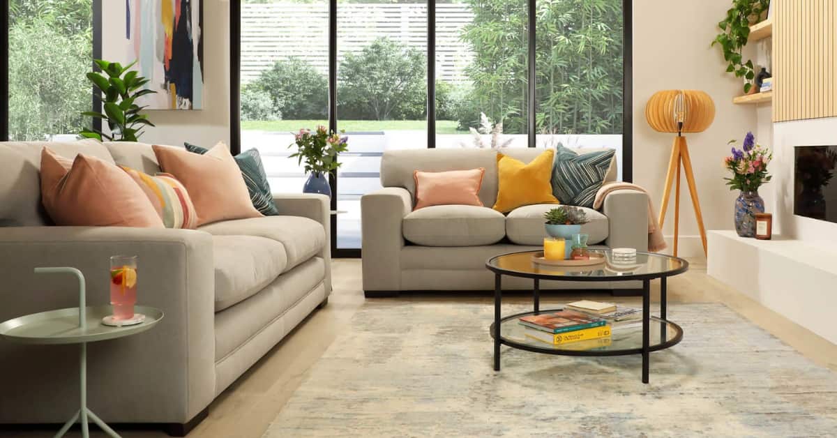 Small living room with concrete floor, grey sofa, neutral cushions, layered rug, bright modern décor”