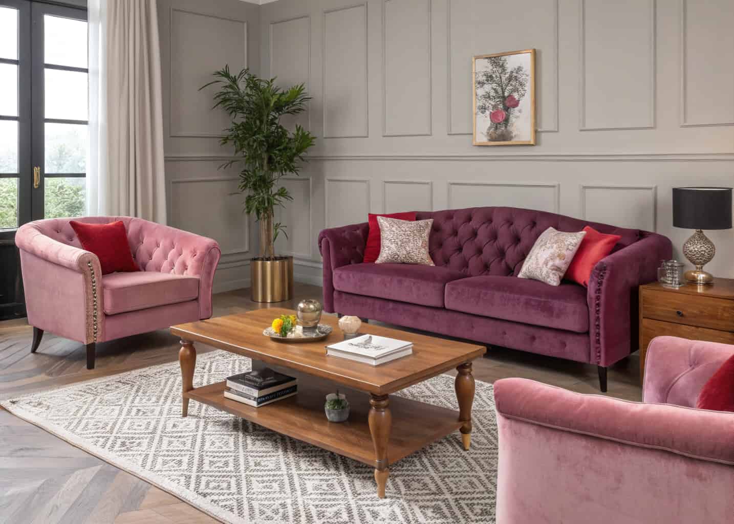 Stylish living room with plum purple velvet sofa, blush pink armchairs, red cushions, wooden coffee table, modern décor”