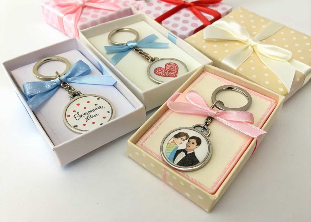 Customized keychains in small gift boxes with ribbons for party favors.”