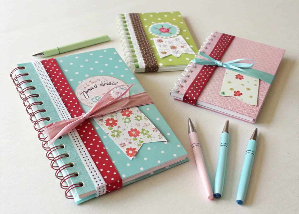 Mini notebooks and pens decorated with ribbons and labels as party favors.”