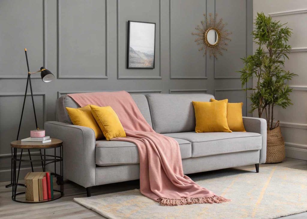 Grey living room with mustard yellow cushions, pink throw blanket, minimalist grey sofa, modern decor, subtle pops of color.