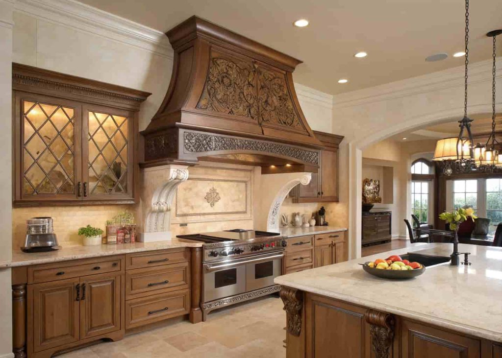 Elegant kitchen with a carved wooden custom range hood, intricate detailing, and classic decor.