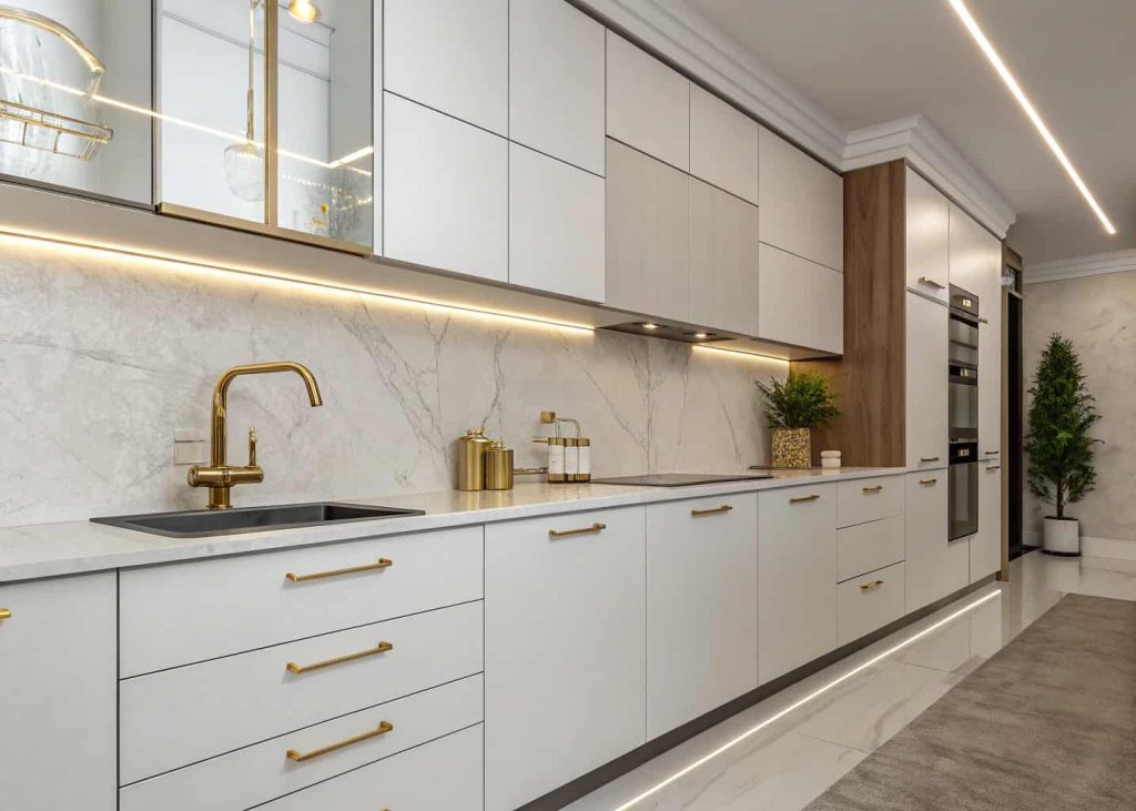 A modern kitchen with metallic gold faucet and cabinet handles, sleek white cabinets, contemporary stylish interior”