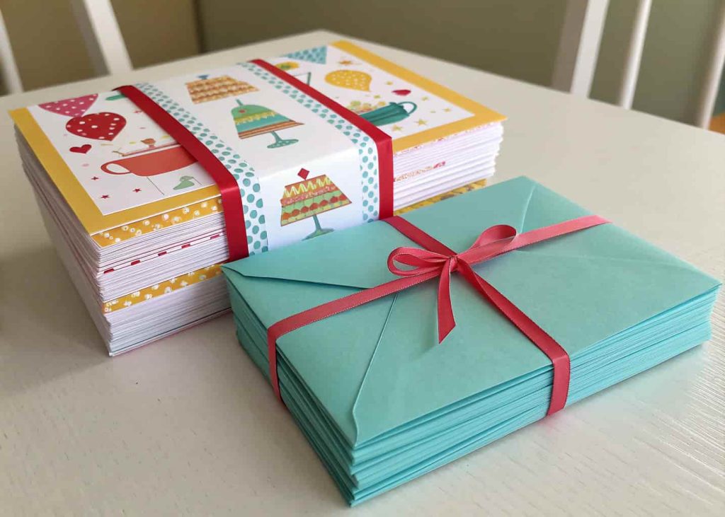 A stack of colorful, themed party invitations on a table with matching envelopes and ribbons."
