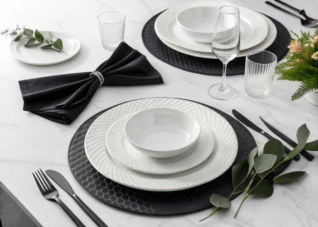 Black and white elegant tablescape with white plates, black napkins, minimalist centerpiece, stylish modern dining table setup.
