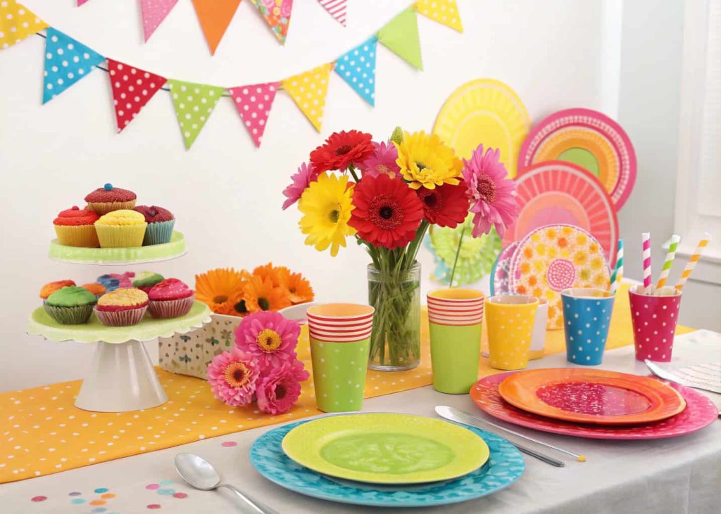 Colorful celebration tablescape with bright plates, vibrant flowers, festive decorations, cheerful party table setup.
