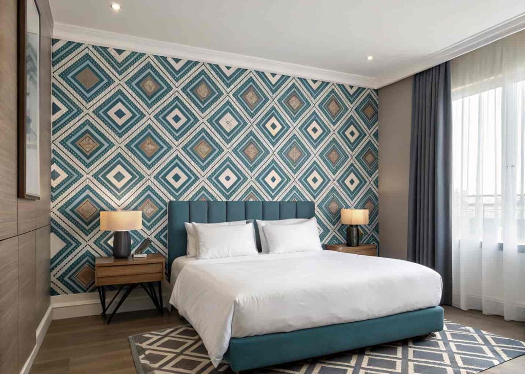 Bedroom with a bold, patterned feature wall behind the bed.