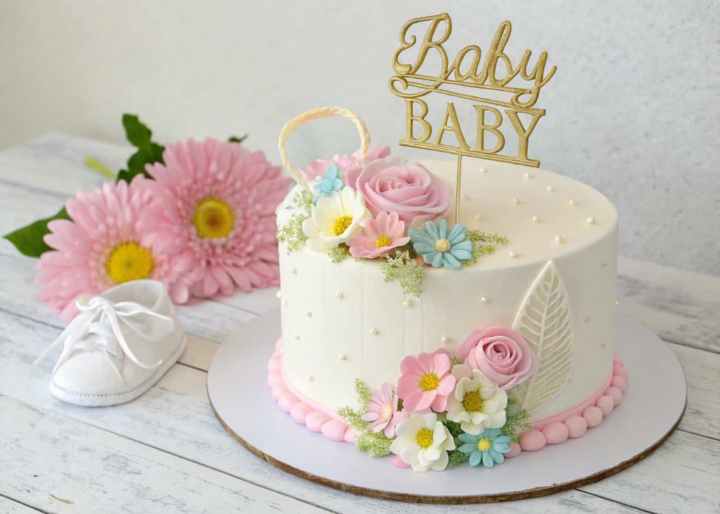simple baby shower cake decorated with flowers and elegant topper