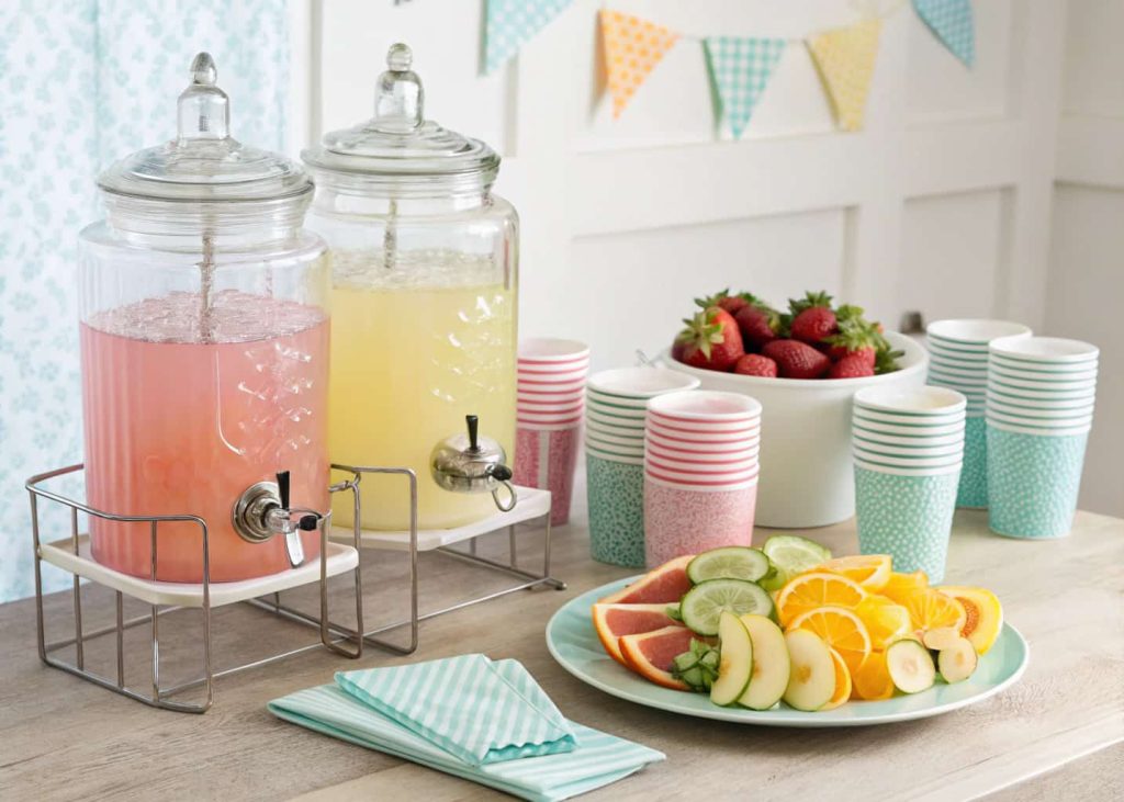 baby shower drink station with glass dispensers, fruit slices, and pastel cups