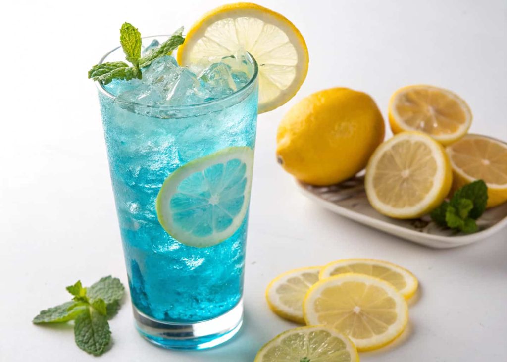 A bright blue lagoon mocktail in a tall glass with lemon slices and ice, glowing vibrant color