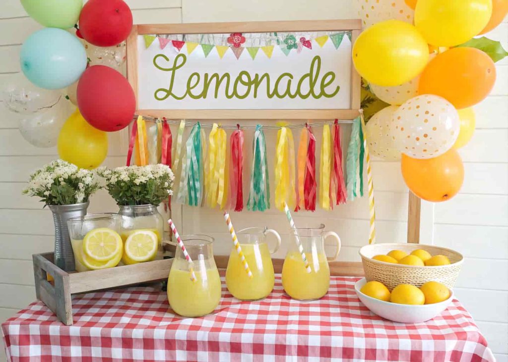A cute lemonade stand setup with bright decorations, pitchers of lemonade, fresh lemons, and a cheerful sign on display