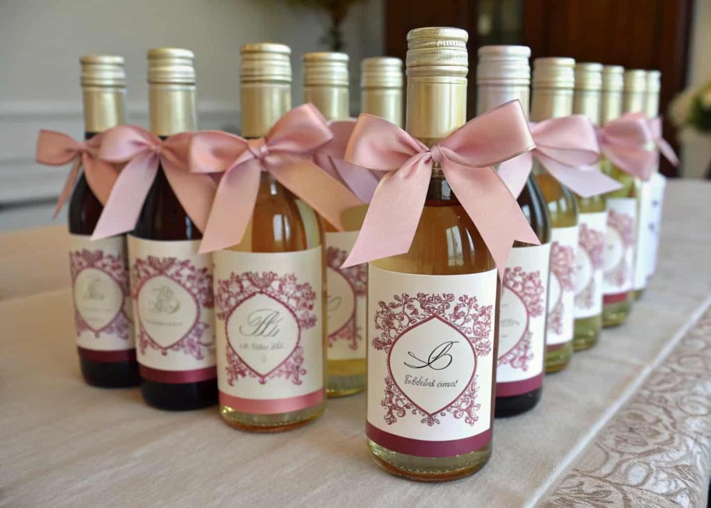 “Mini wine bottles with custom labels and decorative ribbons as party favors.”