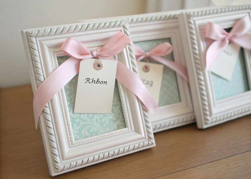 “Small decorative photo frames with ribbons and tags as elegant party favors.”