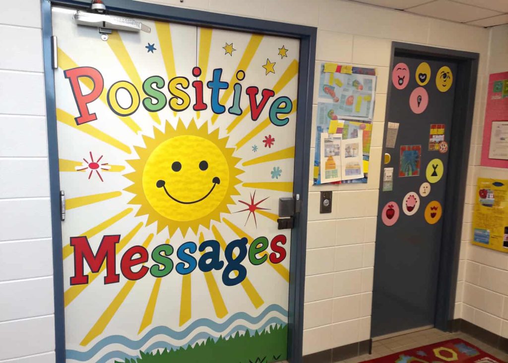 classroom door with big smiling sun, bright yellow rays, positive messages, cheerful design