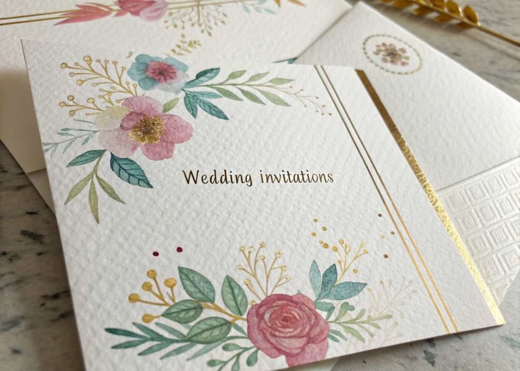Elegant custom wedding invitations with watercolor designs and gold foil lettering on textured paper.