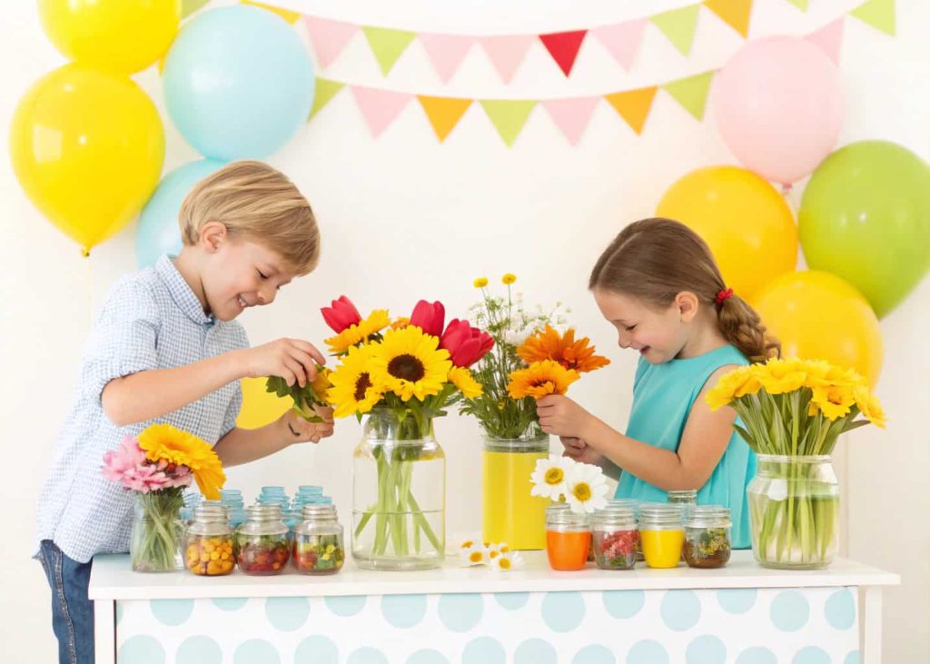 Mini DIY flower bar for kids, small jars with sunflowers, daisies, and tulips, child-friendly setup, colorful and playful.