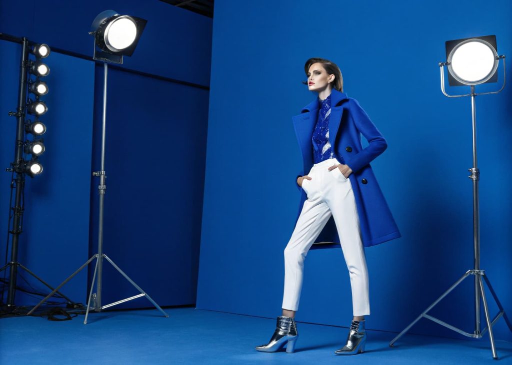 Bold electric cobalt blue fashion editorial, saturated deep blue background, striking contrast with white and metallic accents, strong directional studio lighting, high-fashion magazine aesthetic, confident and powerful visual energy, modern graphic composition.