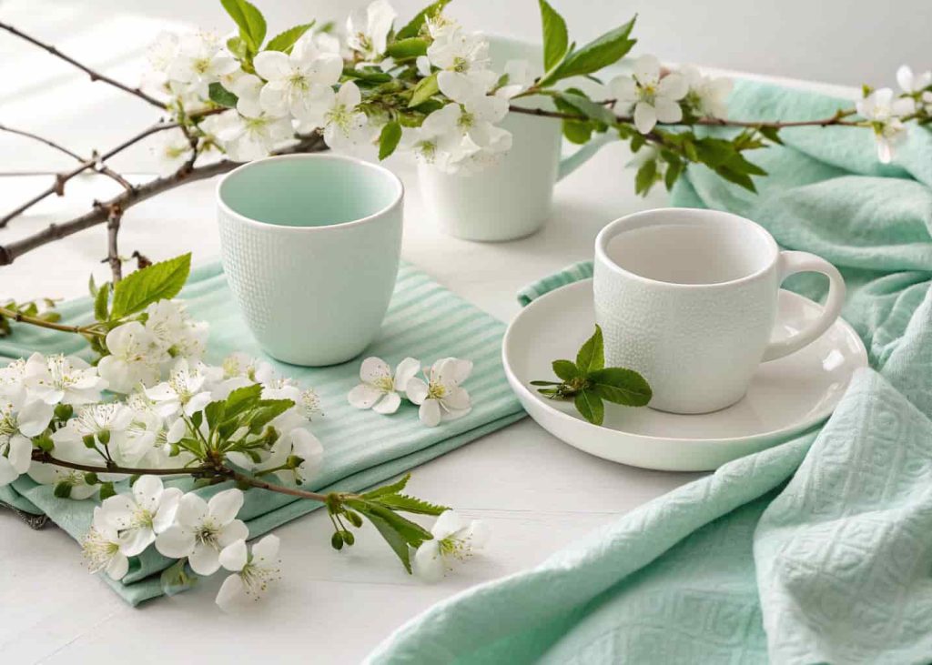 Mint green and white spring color palette, clean aesthetic flatlay with white ceramic cups, mint green cloth, fresh flowers, bright natural light, minimalist spring styling