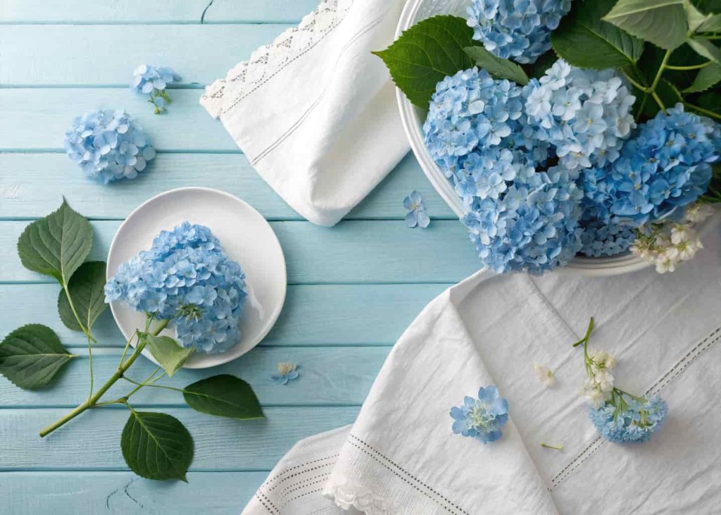Sky blue and soft white color palette, spring aesthetic flat lay with blue hydrangeas, white linen fabric, light wooden surface, soft daylight photography, clean and airy mood