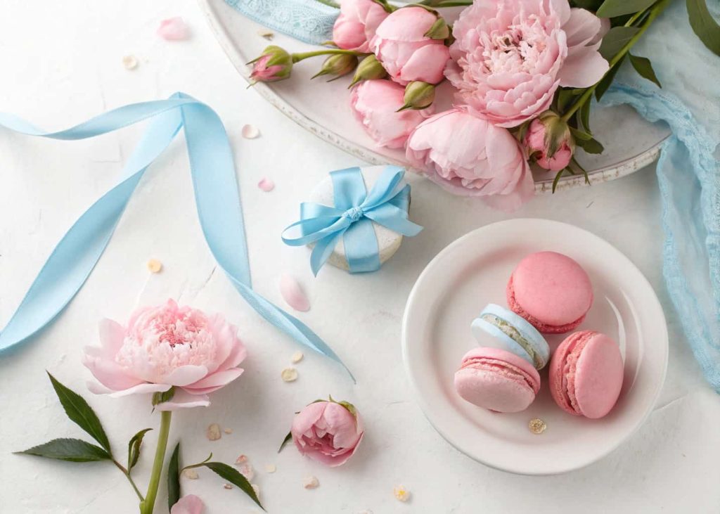 Baby blue and soft pink spring color palette, sweet pastel flat lay with pink peonies, blue ribbon, white background, delicate spring aesthetic, soft studio lighting photography