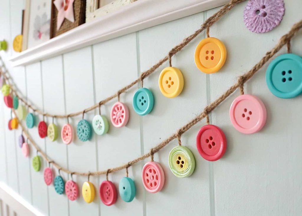 Colorful mismatched button garland on rustic twine, featuring buttons in all shapes and sizes in pastels and brights, hanging in a cozy craft room or children's bedroom, vintage retro spring decor aesthetic, warm and cheerful mood.