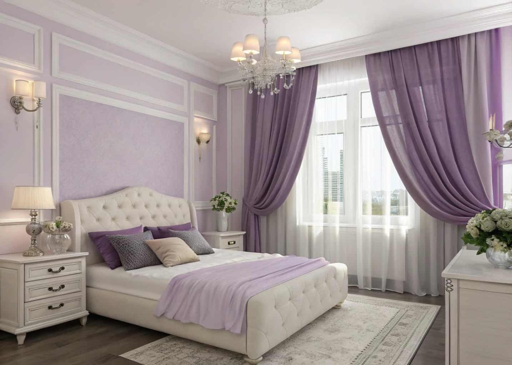 A soft and dreamy bedroom with lavender mist walls, flowing white and lilac curtains, a white upholstered bed with soft purple and cream pillows, a chrome or silver bedside lamp, fresh white flowers in a vase, and a peaceful, ethereal early morning light filling the room