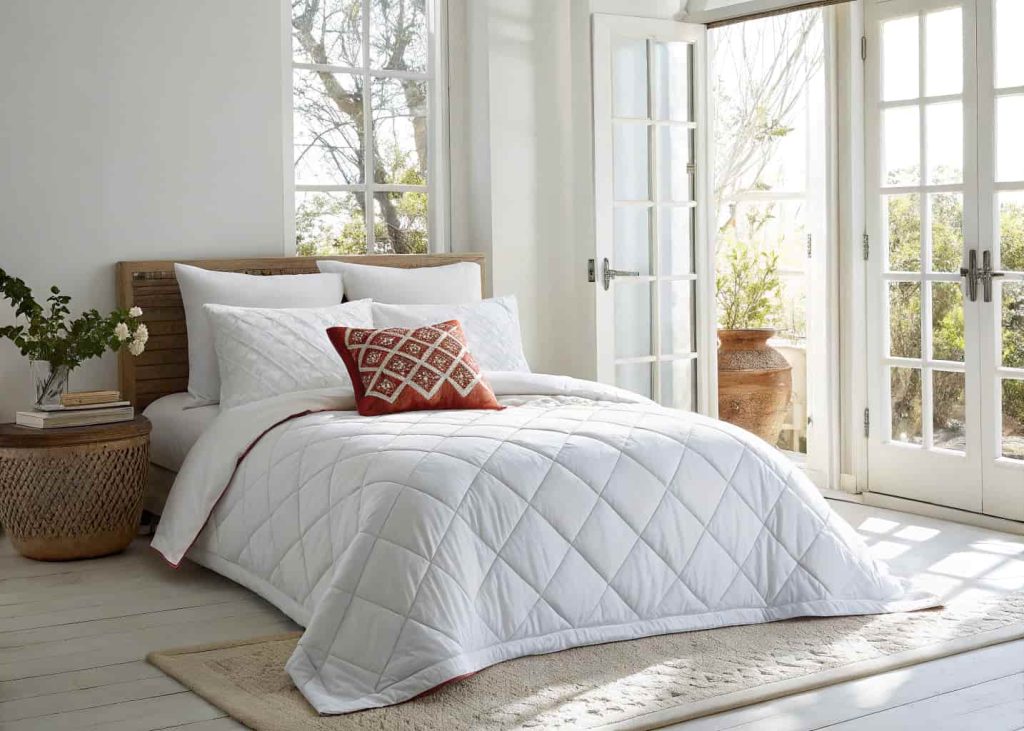 A single bold decorative accent pillow placed casually in the center of a beautifully made bed, high-quality white duvet, minimal bedroom, natural light, effortless styling, clean interior photography