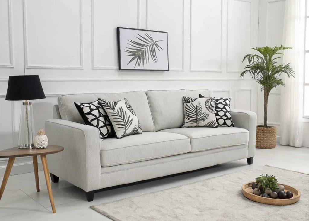 A light gray modern sofa with black and white graphic print throw pillows, minimalist contemporary living room, clean aesthetic, high-contrast interior photography