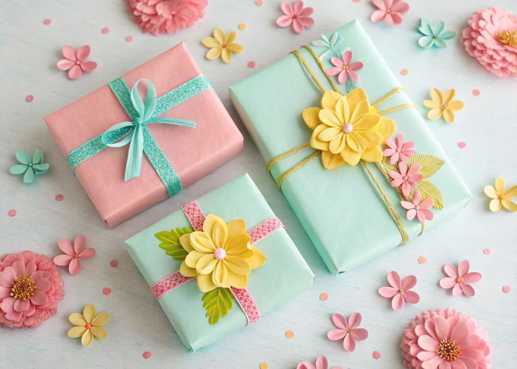 Small colorful tissue paper flowers in pink, yellow, and mint, used as gift toppers on wrapped presents, tied with ribbon, flatlay on a pastel background, festive and sweet craft photography.