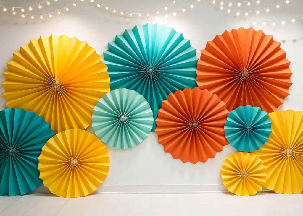  A colorful wall display of large paper fan accordion flowers in bold yellow, teal, and orange shades, arranged symmetrically on a white backdrop, bright studio lighting, modern festive decoration, flat lay aesthetic.