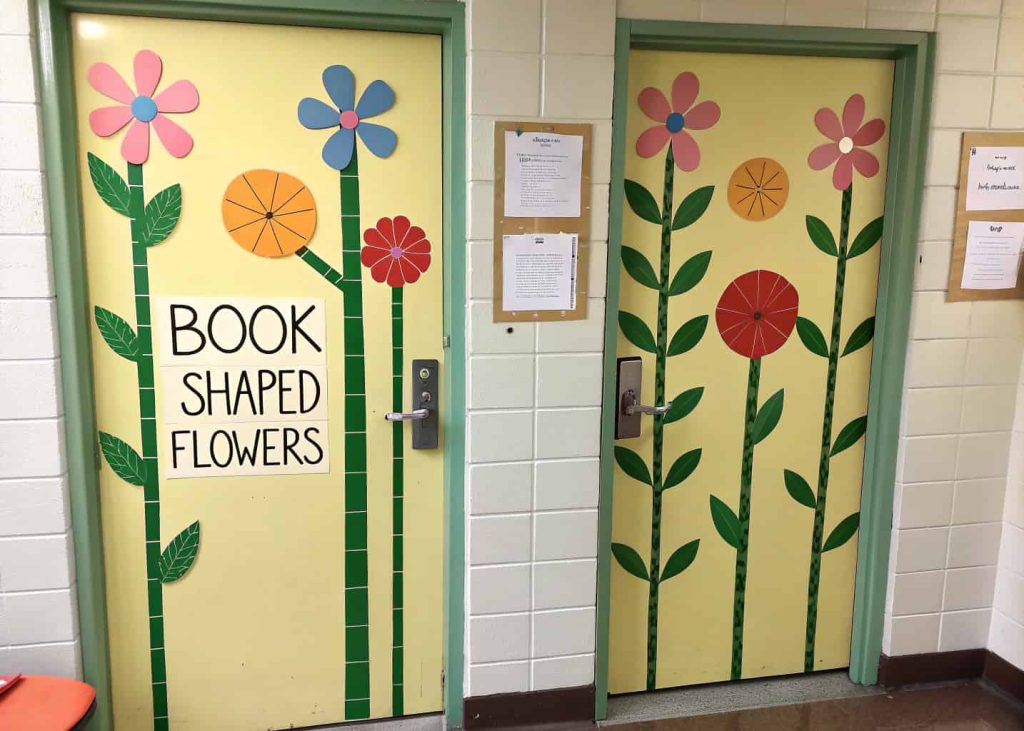 Classroom door with book-shaped flowers, green stems, leaves, and students’ names written on the books.