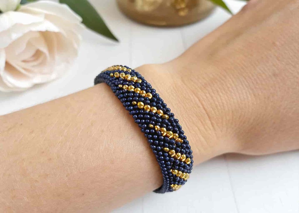 Navy blue and gold seed bead stretch bracelet worn on a woman's wrist