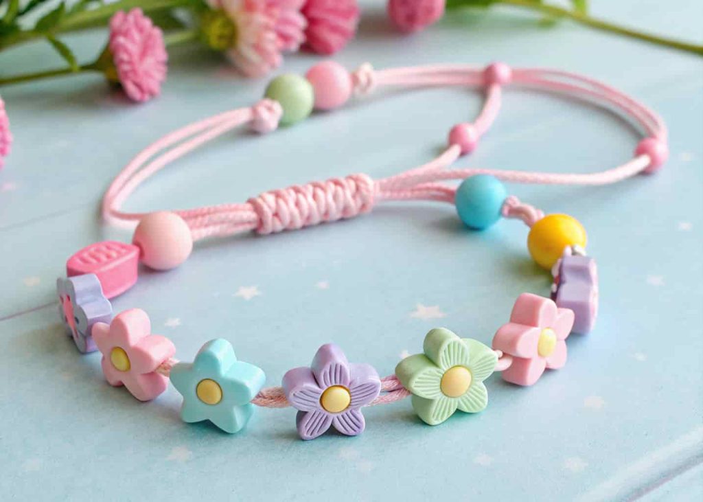 Pastel clay bead bracelet with flower and star shapes on pink cord flat lay