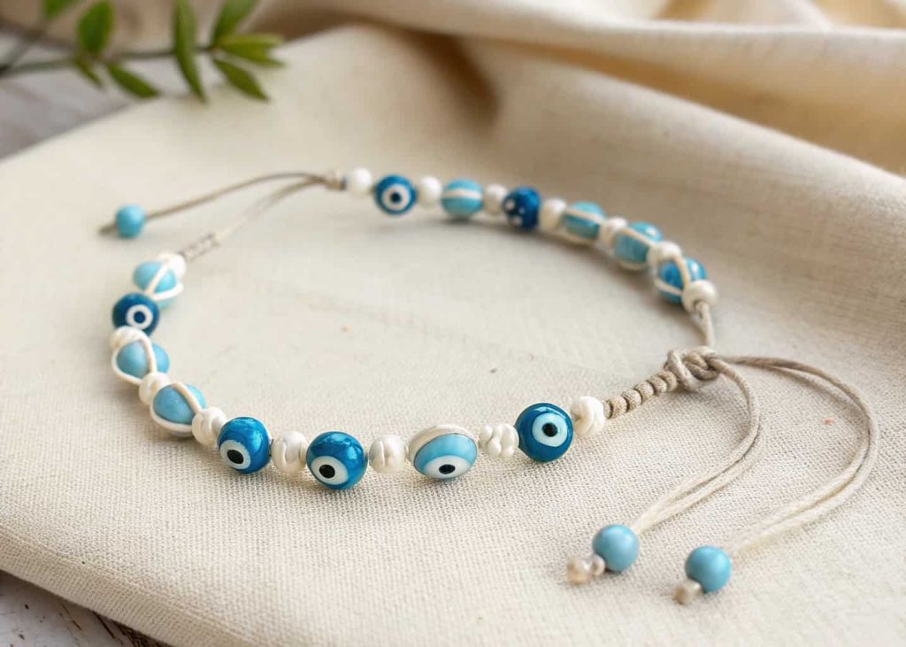 Minimalist evil eye bead bracelet in blue and white on beige linen background