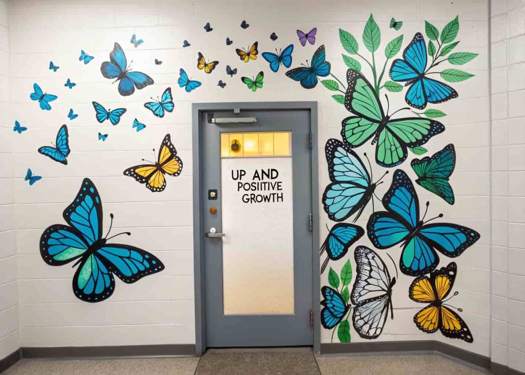Door covered in large, colorful butterflies, some with motivational words, appearing to fly upwards.