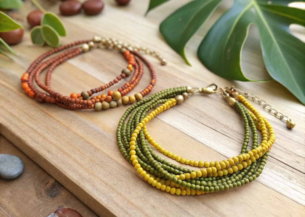 Layered bohemian seed bead bracelets in earthy tones on a wooden surface