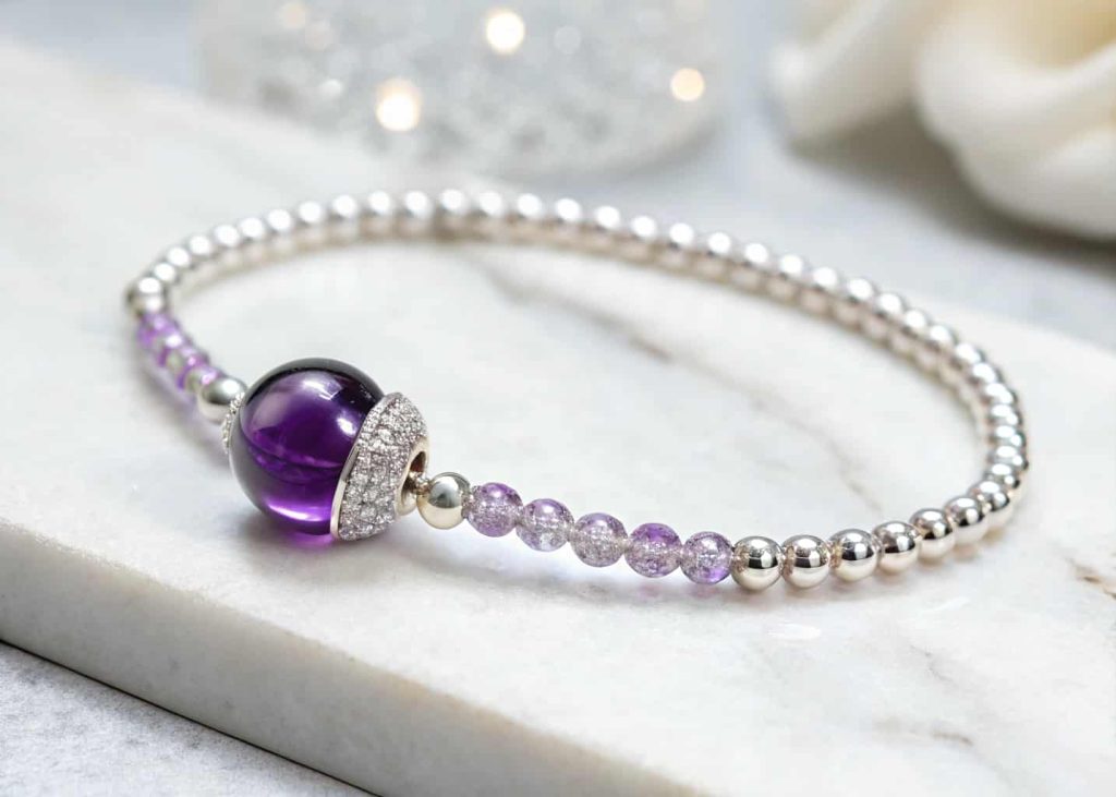 Delicate birthstone bracelet with purple amethyst center bead and clear crystal beads on white marble