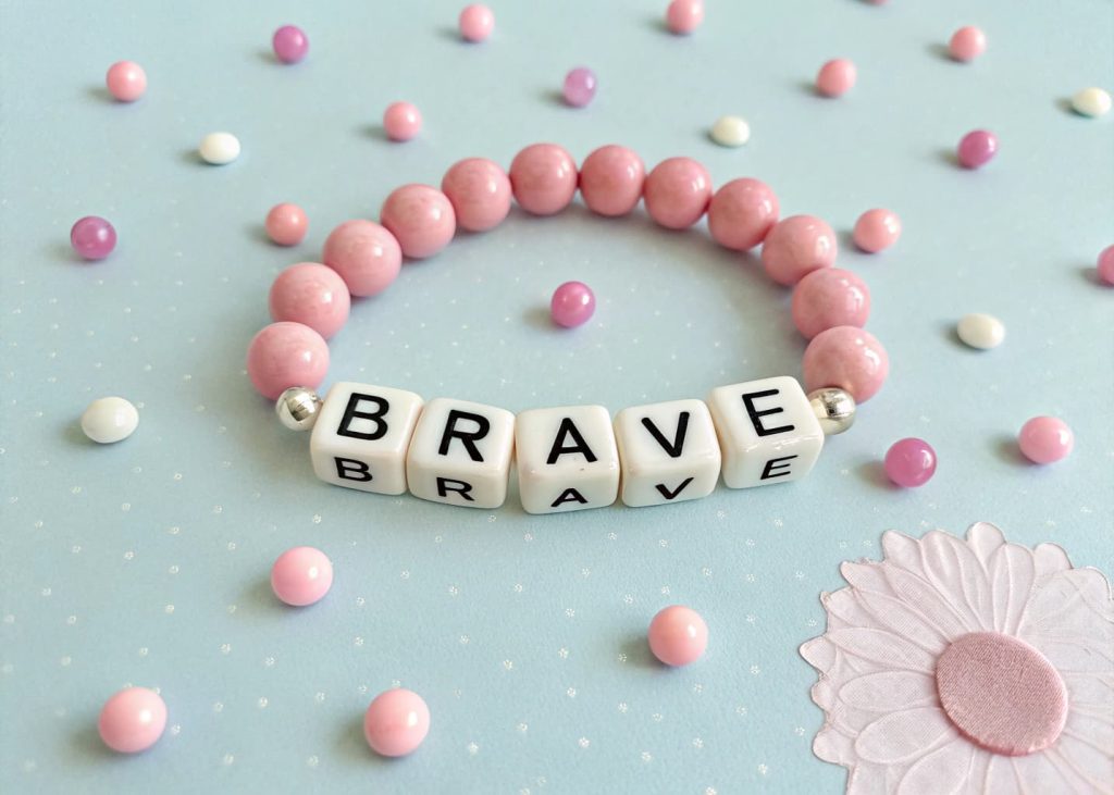 Personalized alphabet bead bracelet spelling brave with white letter beads and pink round beads