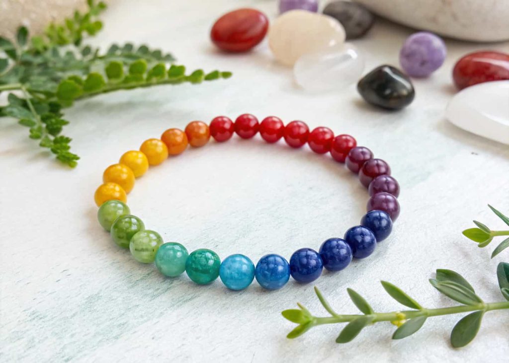 Seven chakra gemstone bracelet with rainbow-colored healing stone beads on white background