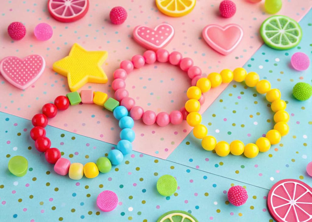 Colorful kids candy bead bracelets with star heart and fruit shaped beads on confetti background