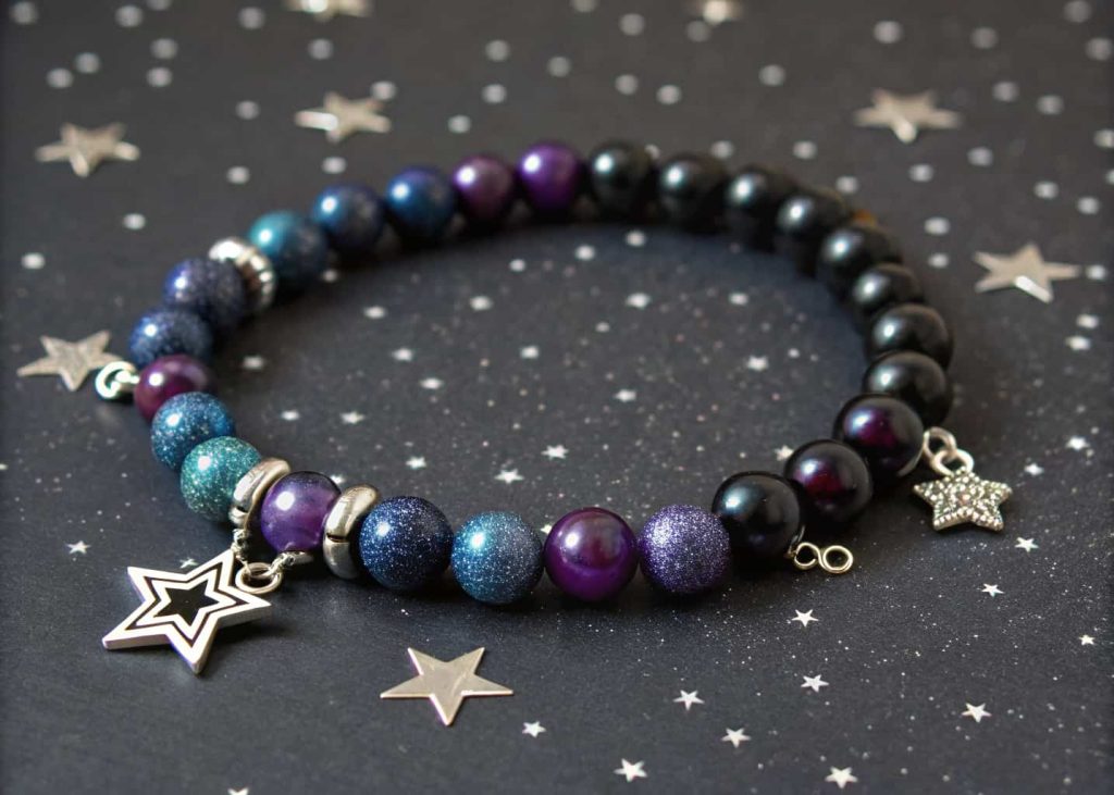 Galaxy-themed bead bracelet with navy purple black and silver beads on dark glittery night sky background